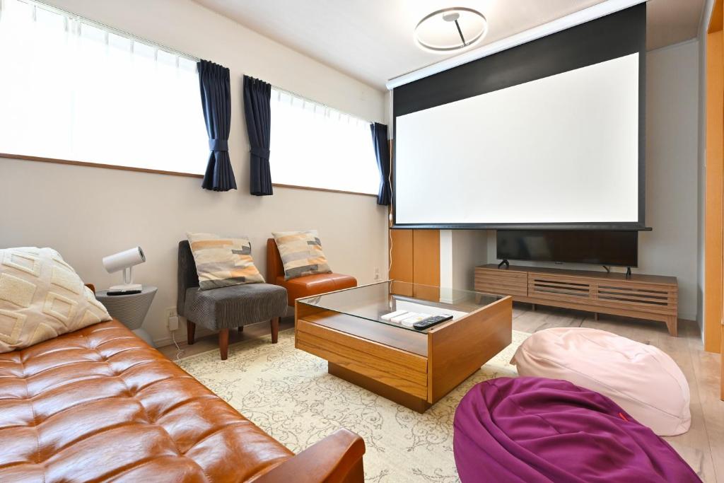 a living room with a couch and a large screen at The triangle hub Miyazaki in Miyazaki