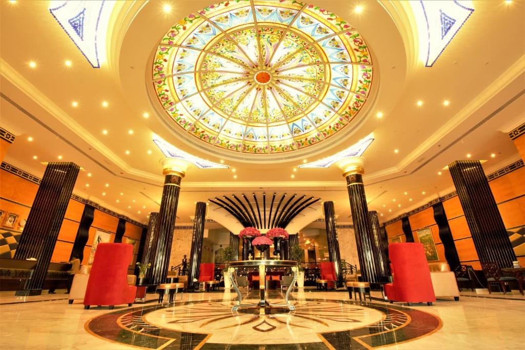 a large lobby with a ceiling with a large window at Red Castle Hotel in Sharjah
