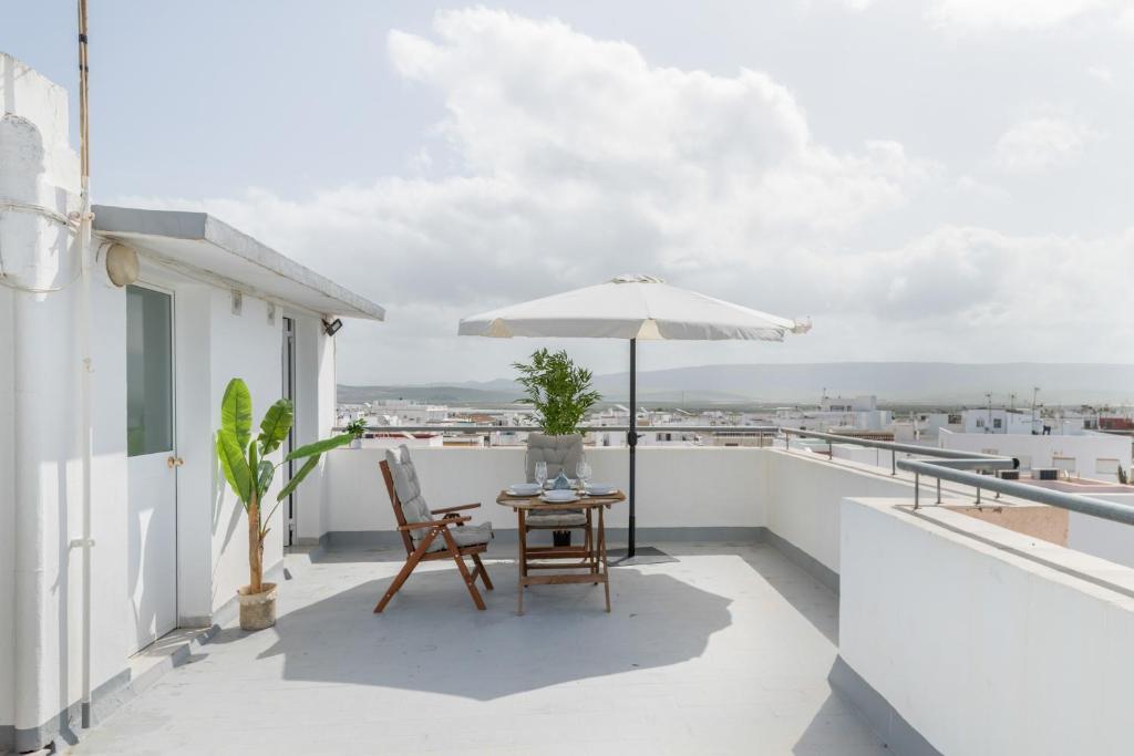a patio with an umbrella and a table on a balcony at Apartamento Almadraba in Barbate