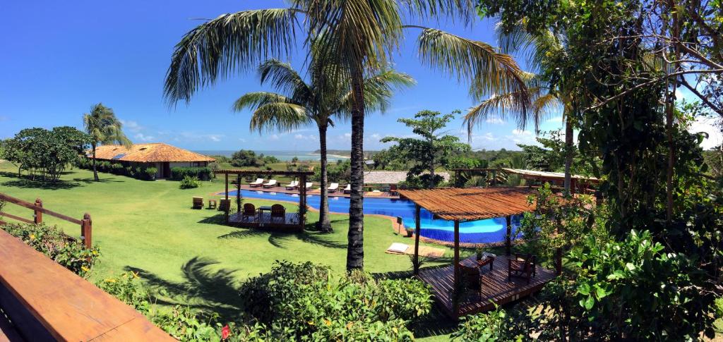 um resort com piscina e palmeiras em Pousada Outeiro em Praia do Espelho