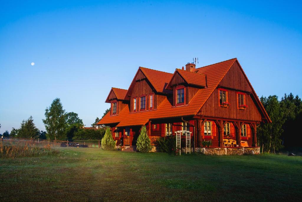 une grande maison en bois avec un toit rouge dans l'établissement Willa Hermanówka, à Ryn