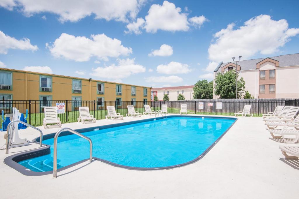 a swimming pool with lounge chairs and a building at Days Inn by Wyndham Joplin in Joplin