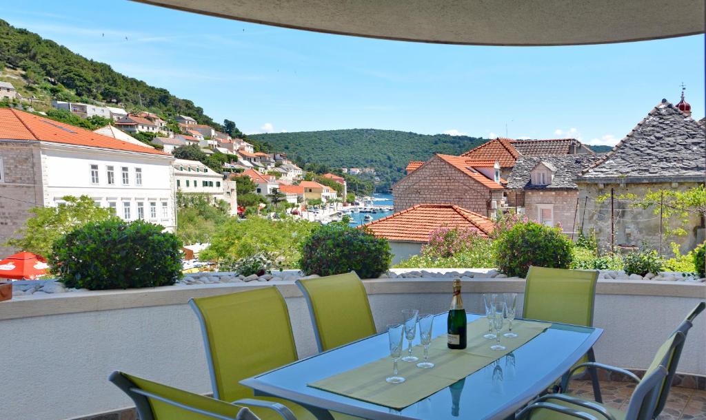 a table with a bottle of wine and chairs on a balcony at Apartments Mladinić in Pučišća