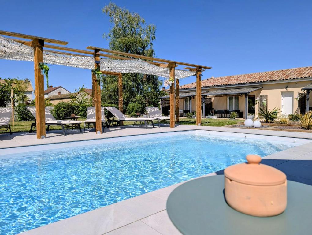 a swimming pool with a pergola next to a house at Gite Les Intemporels in Cuisery