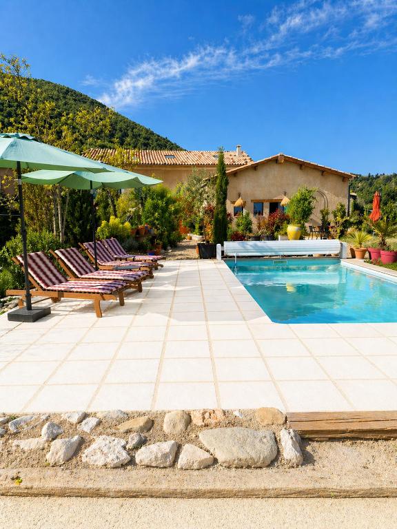 a pool with chairs and umbrellas in front of a house at le clos d'Yrem in La Rochegiron