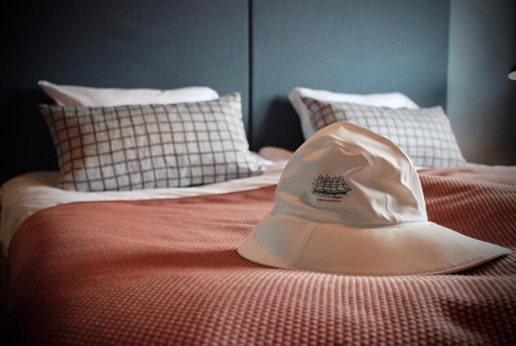 a white hat is sitting on a bed at Grundéns Hotell in Grundsund