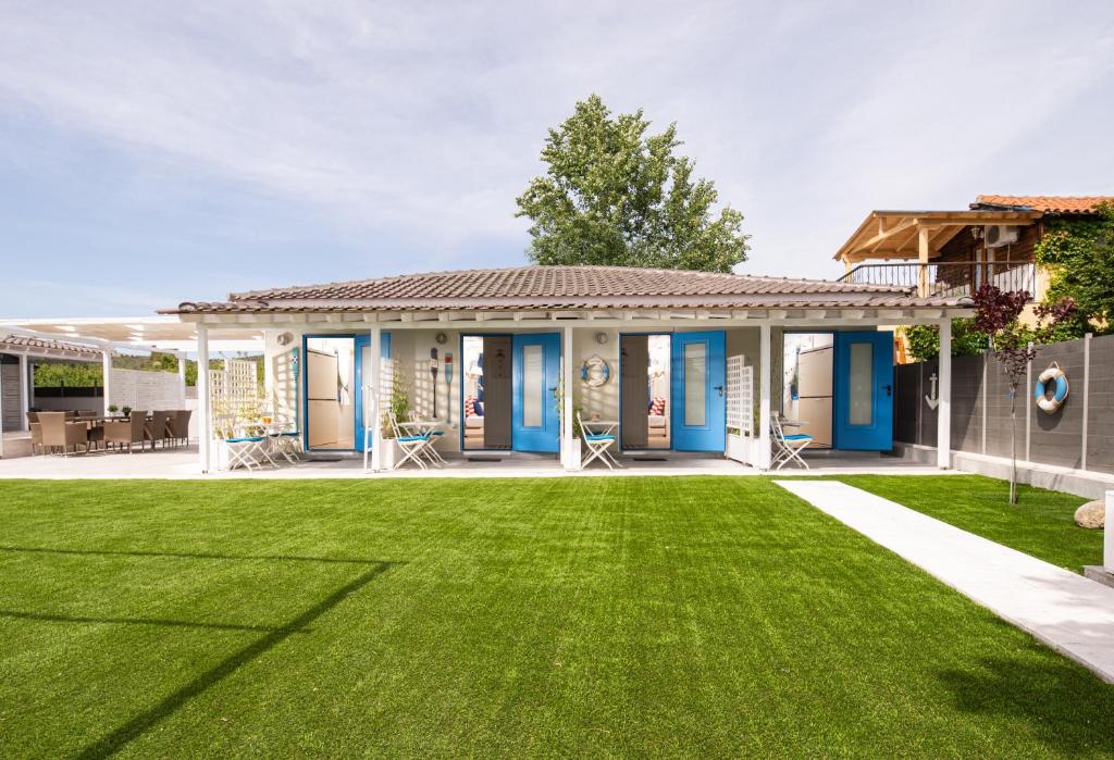 a house with a green lawn at Nautical Toroni Rooms in Toroni