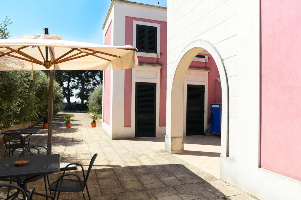 a patio with an umbrella and tables and chairs at The Aia in Nardò