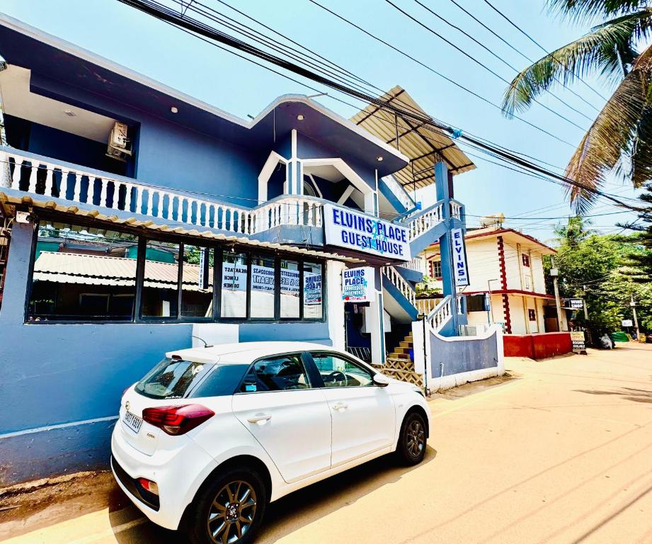 a white car parked in front of a blue building at FabHotel Elvin's Place in Calangute