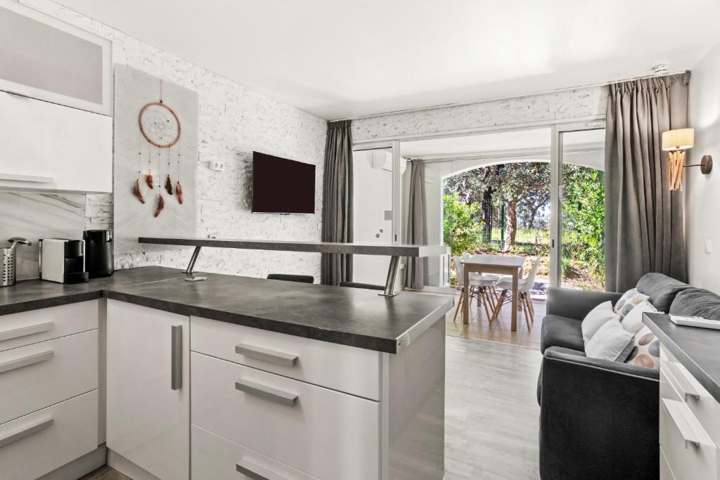 a kitchen with white cabinets and a living room at Apartment – Restanques – Swimming in Grimaud