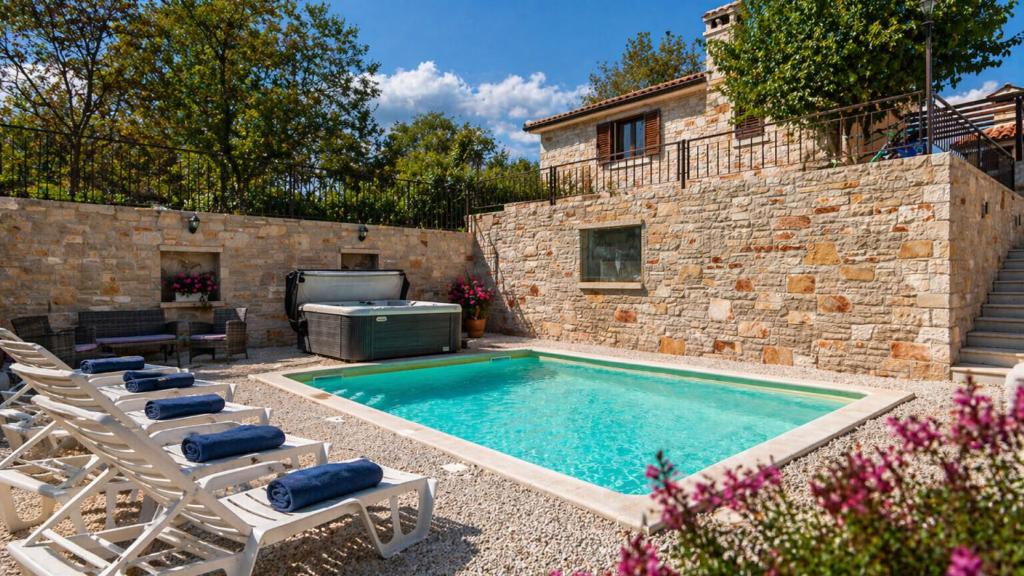 a swimming pool with lounge chairs and a house at Villa Zebo by Villas Guide in Barban