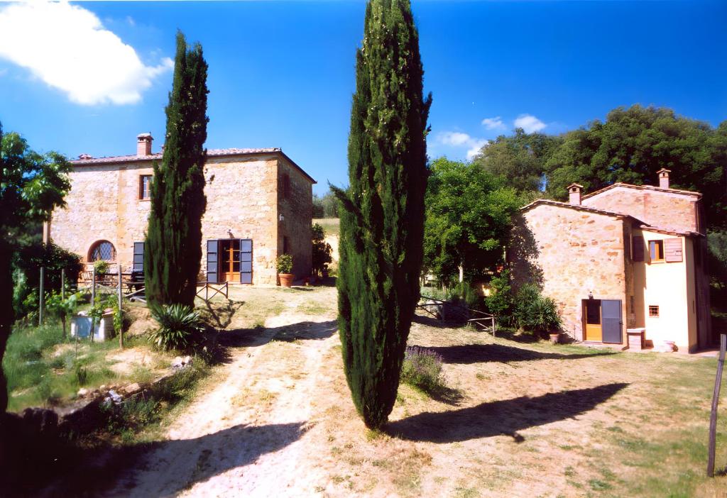 a house with two tall trees in front of it at Capanne di Sopra in Torrita di Siena