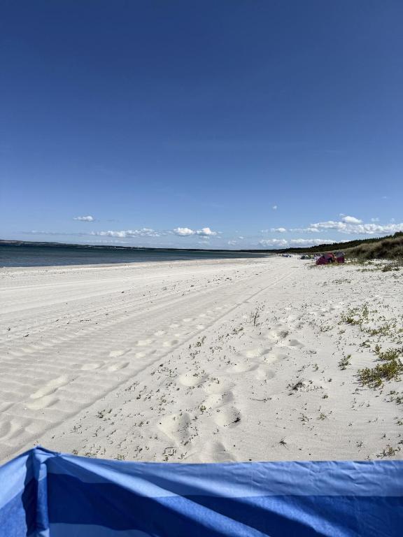 a sandy beach with a blue tent on it at Ferienwohnung Sonnenschein in Dranske