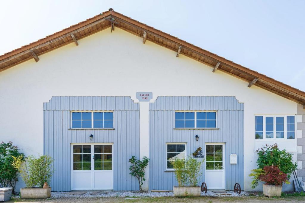 a white house with blue windows at Gite de Laluby in Arx