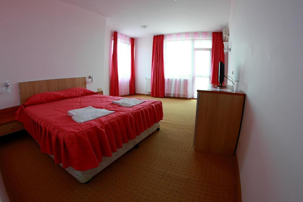 a bedroom with a red bed and red curtains at Hotel Akre in Kavarna