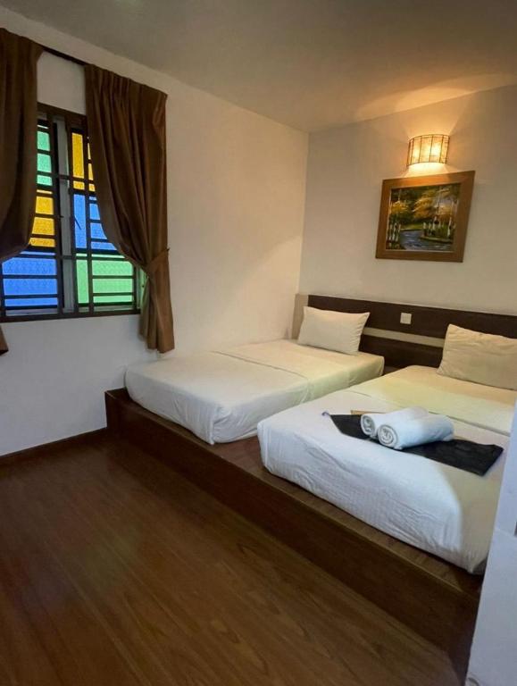 two beds in a room with two windows at Hotel O Village in Baling