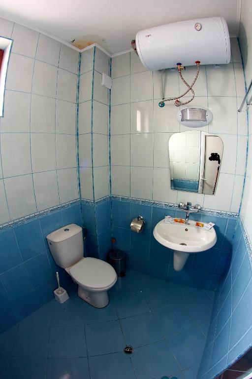 a blue tiled bathroom with a toilet and a sink at Hotel Akre in Kavarna