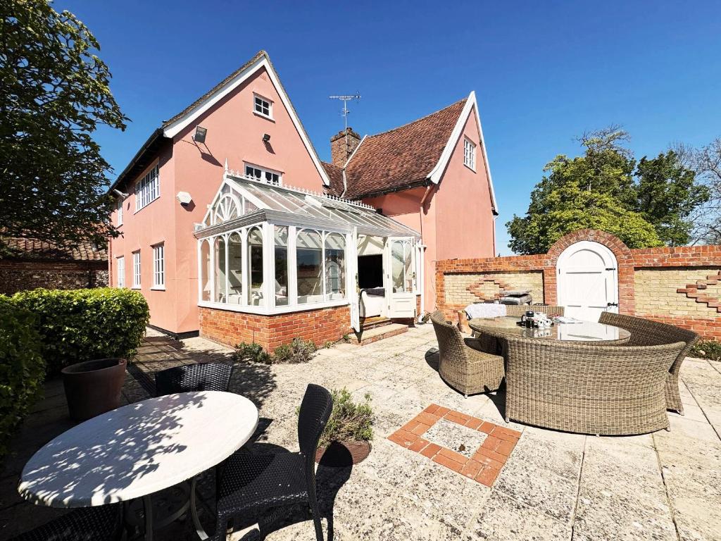 a patio with tables and chairs in front of a house at Cottage Farm by The Suffolk Cottage Collection in Offton