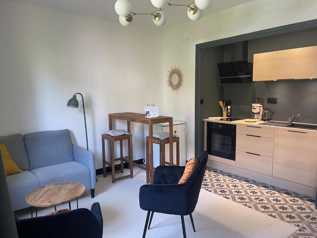 a living room with a blue couch and a kitchen at L'instant cocon in Beaumont