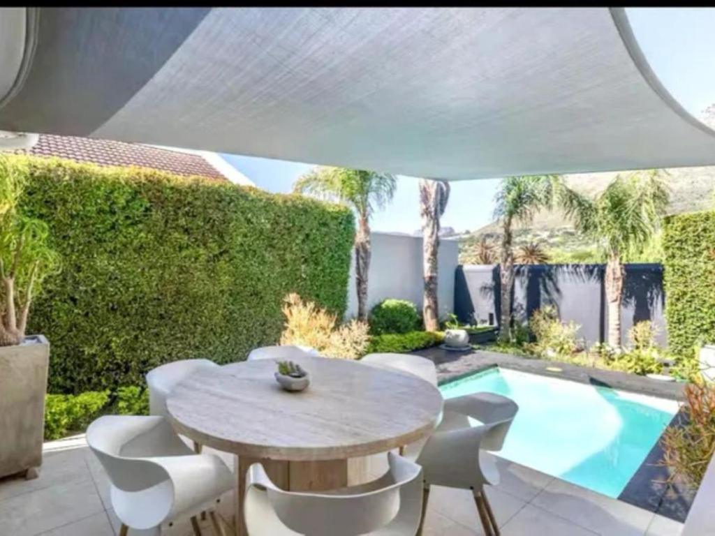 a patio with a table and chairs and a swimming pool at Hout Bay Gem 61 Milner in Hout Bay