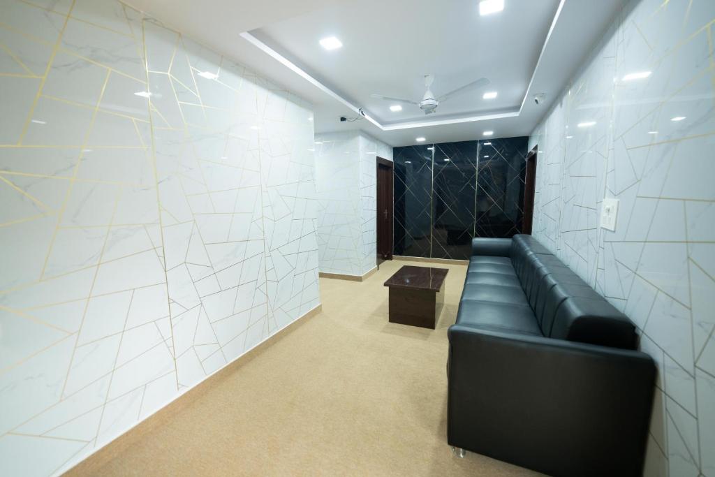 a black couch in a room with white tiles at Sri Sai Saara Inn in Bangalore