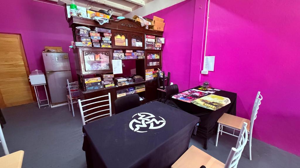 a room with purple walls and tables and chairs at Pink Kraken Hostel in Ban Nong Chaeng