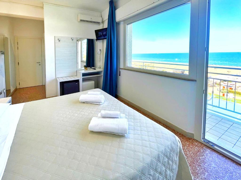 a bedroom with a bed and a large window with the beach at Hotel Degli Angeli Riccione in Riccione