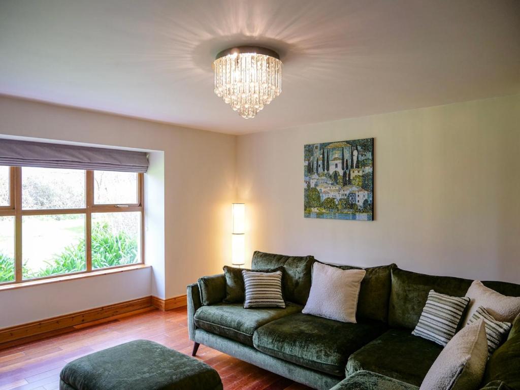 a living room with a green couch and a chandelier at Just Beyond Dingle in Dingle