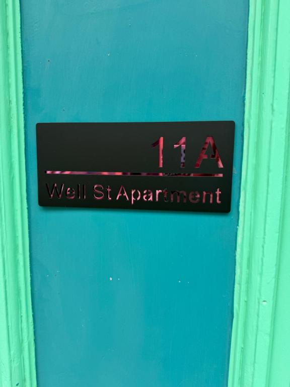 a sign on a blue door with the time on it at Well St Apartment in Moffat