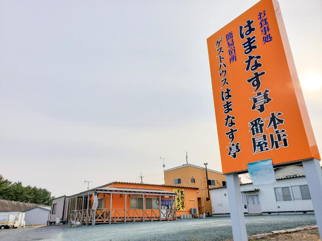 an orange sign in front of a building at ゲストハウスはまなす亭 in Jōnai