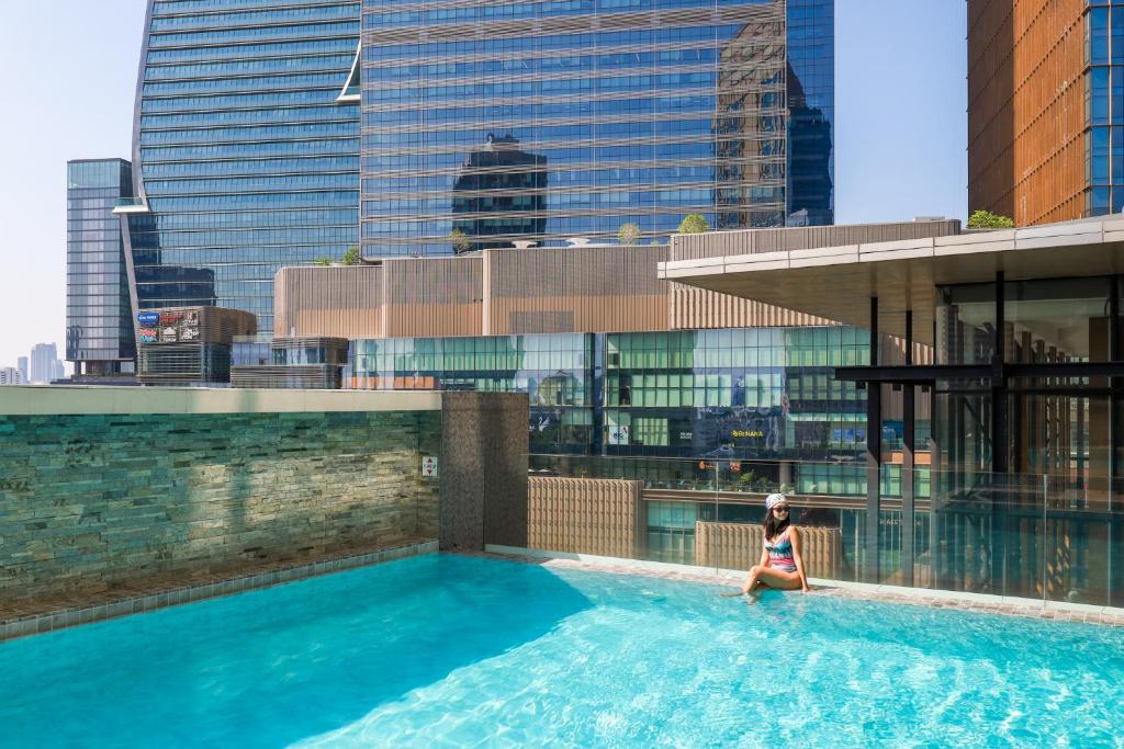 A rooftop pool with city views, a tiled feature wall, and a glass-sided pool building.