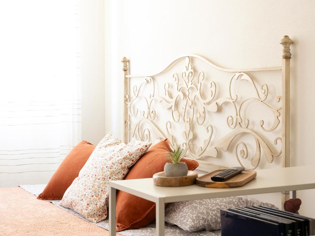 a bed with a white headboard and a table at La Chicca Appartamento Superior Fucecchio in Fucecchio