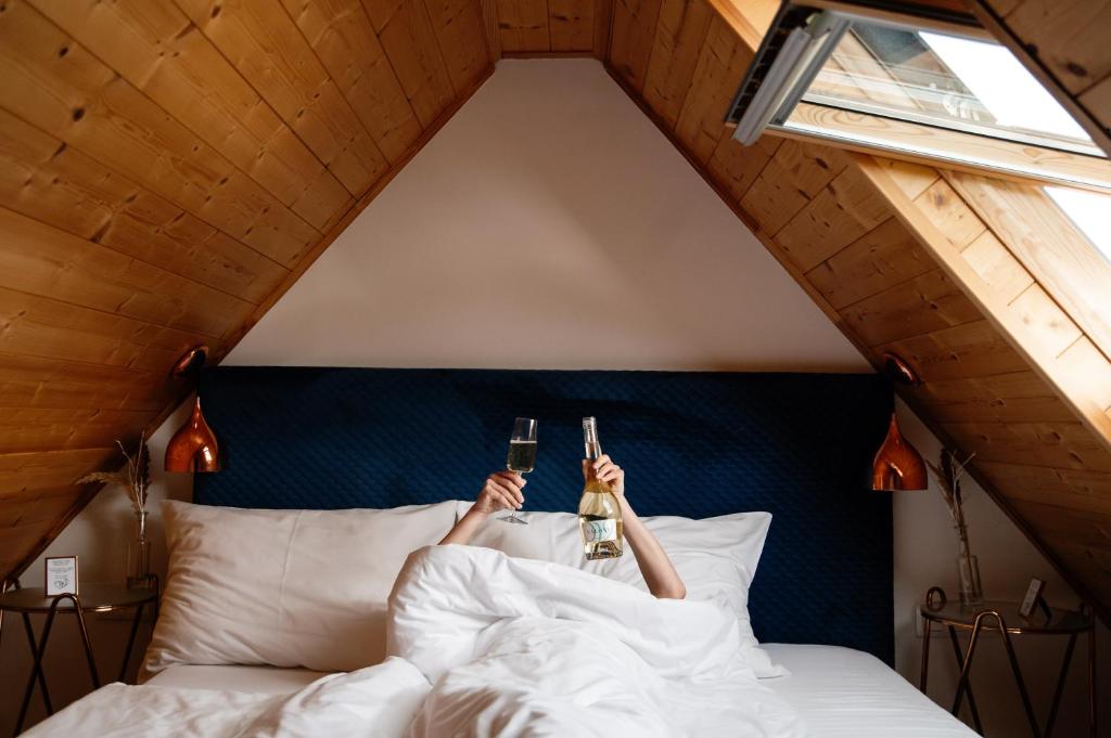 a person laying in bed with two bottles of beer at VALONÉ Villány in Villány