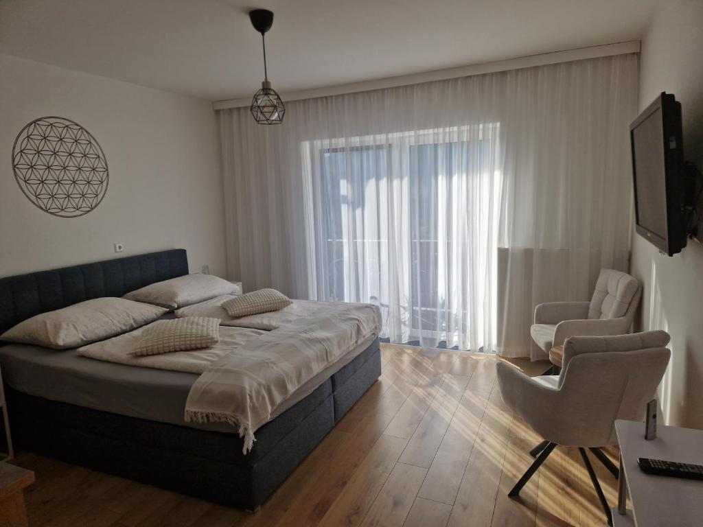 a bedroom with a bed and a chair and a window at Haus Rupitsch in Winklern
