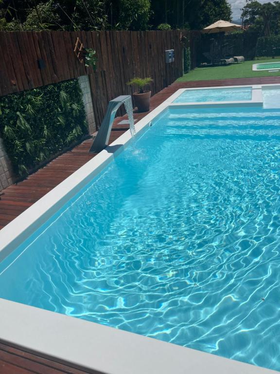a swimming pool with a bench in the water at Pousada Encantos do Rosa in Imbituba