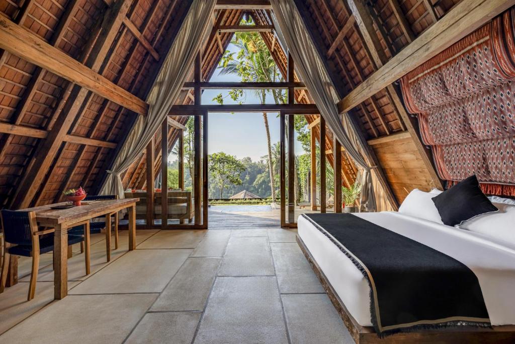 a bedroom with a bed and a table in a building at Bumi Kabins Ubud in Tegalalang