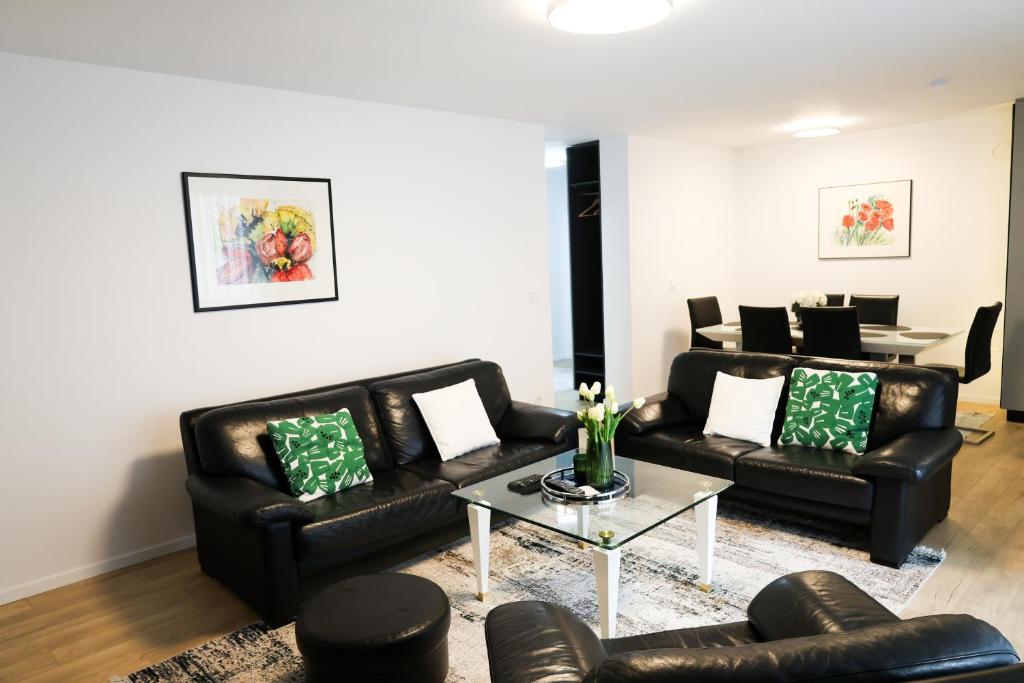 a living room with two black leather couches and a table at Nest apartament in Peje