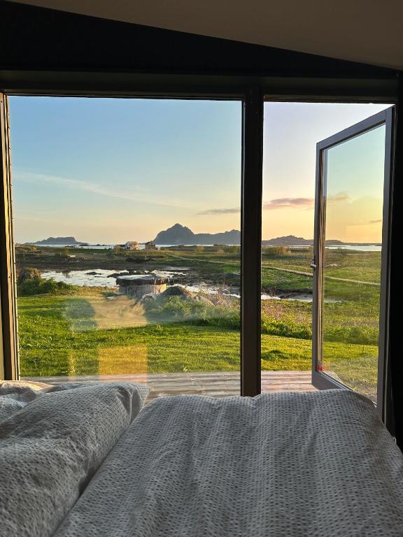 a bedroom with a bed and a large glass window at Skagenhaugen Private Lodge in Bø i Vesterålen
