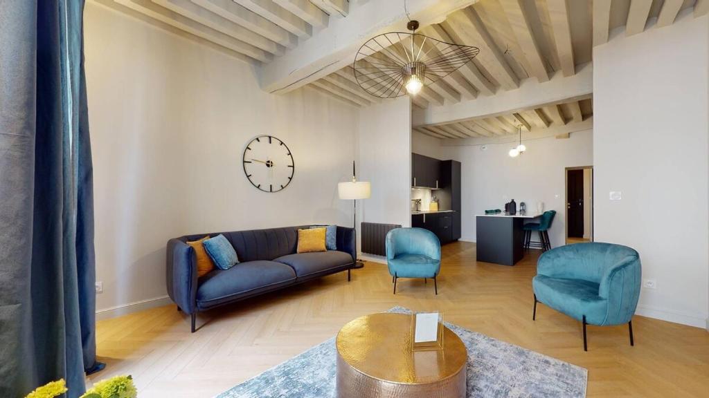a living room with a couch and a clock on the wall at Le Petit Piron in Dijon