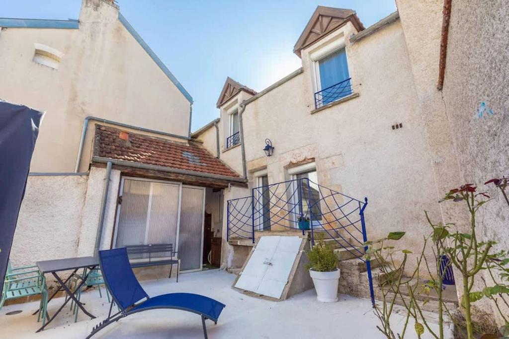 a patio with two chairs and a table and two buildings at La Cabotte d'Ahuy in Ahuy