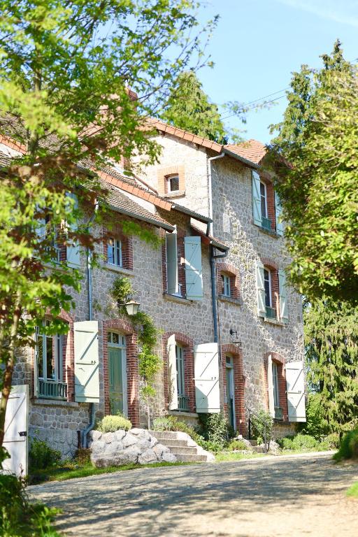 a large stone house with green doors and windows at Bon Chez Nous in Saint-Amand-Jartoudeix