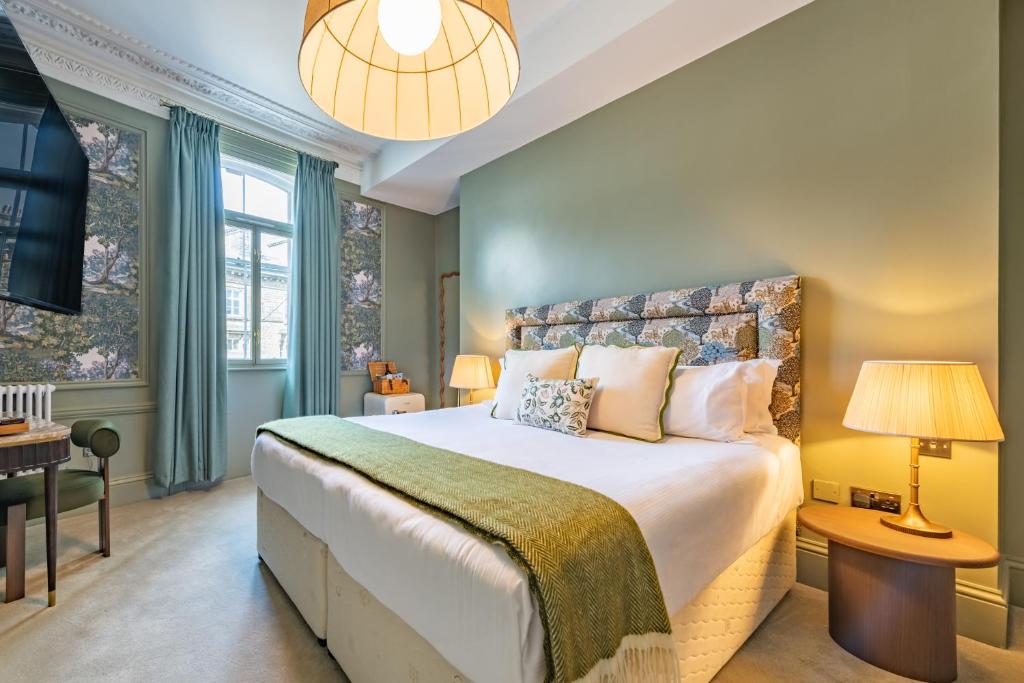 a bedroom with a large bed and a chandelier at Crescent Inn by Maison Pierre in Ilkley