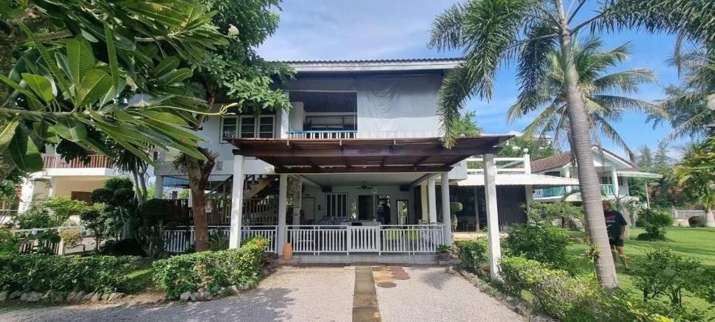 a house with a wooden porch and palm trees at The Rich Instantly Home in Sathani Huai Yang