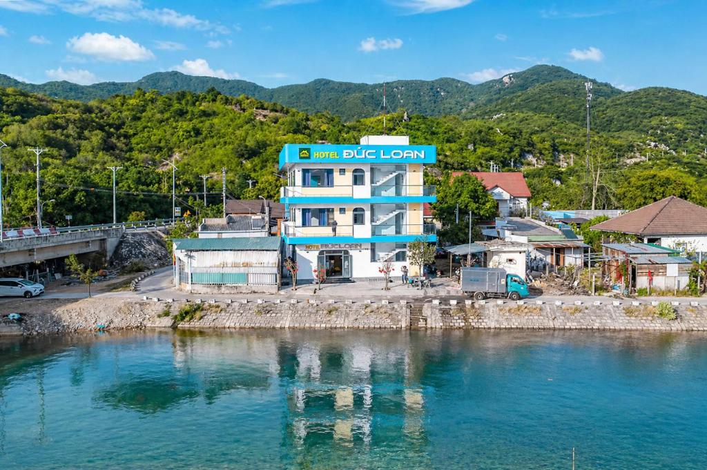 a blue and white building next to a body of water at Đức Loan Hotel Vĩnh Hy in Ninh Hải