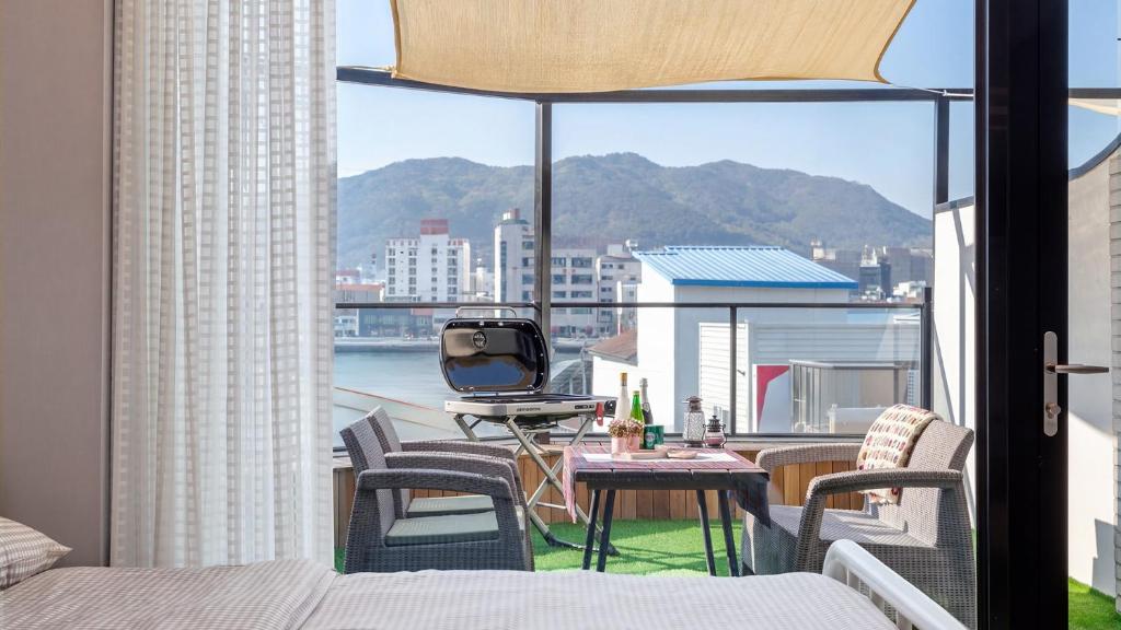 a balcony with a bed and a table and chairs at Tongyeong Present Gamsung Pension in Tongyeong