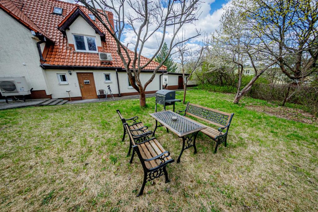 three benches and a table in a yard with a house at Stara Piekarnia - Jagiellońska in Olsztyn