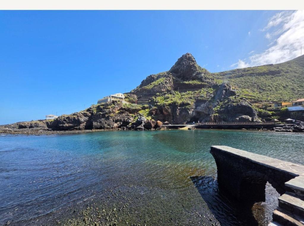 a bench sitting next to a body of water with a mountain at FINCA LA JORADITA in Tamaduste