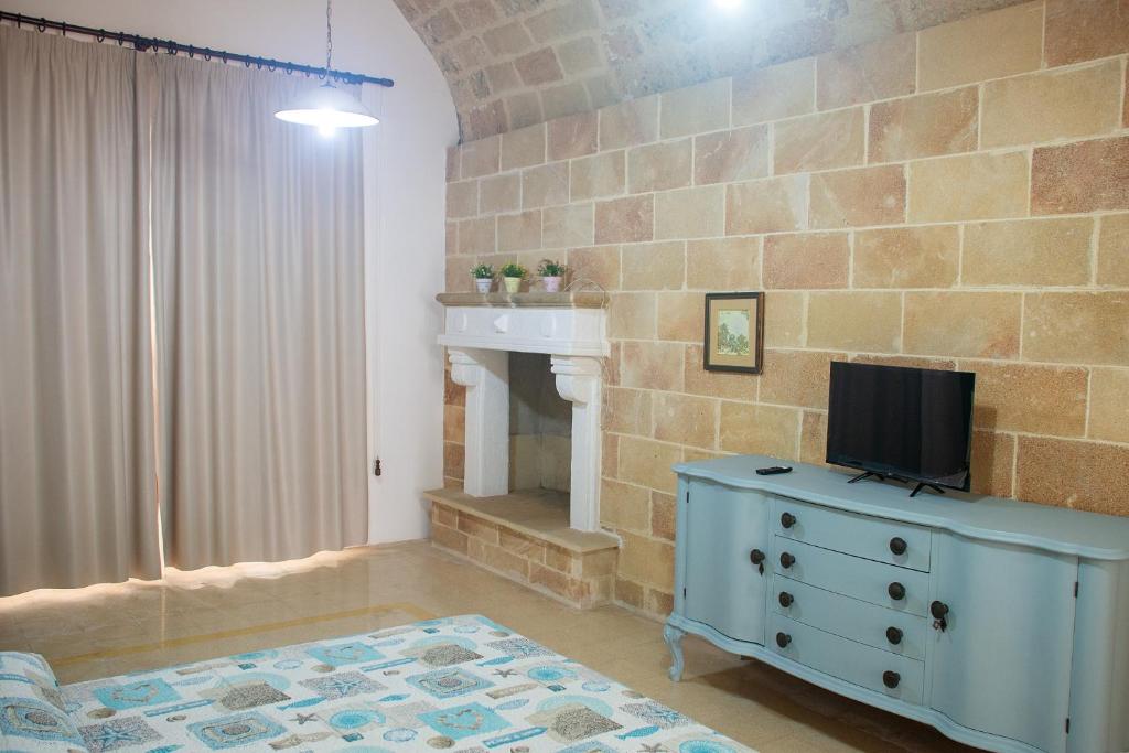 a living room with a television on a dresser with a fireplace at Felline centro storico in Felline