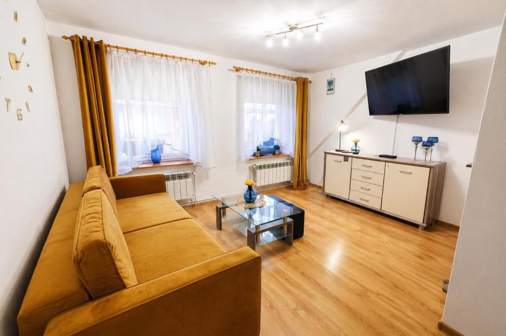 a living room with a couch and a tv at Apartament Sprężynka in Mrągowo