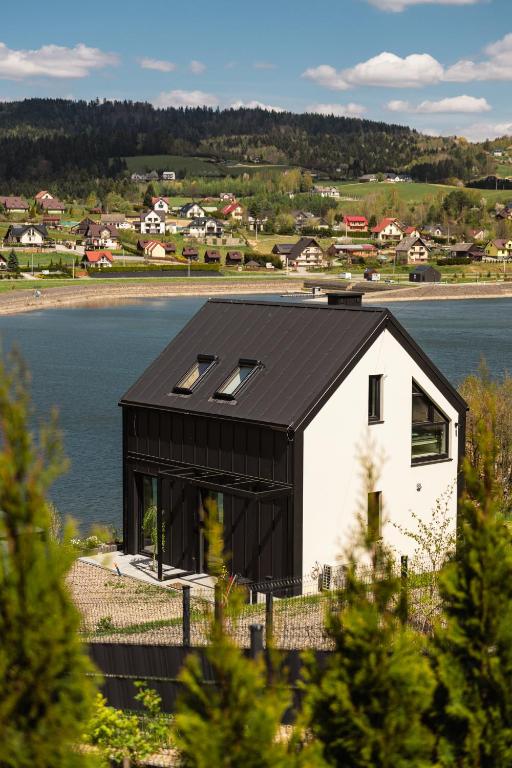 a black and white house next to a body of water at Gródek & Ogródek in Gródek Nad Dunajcem